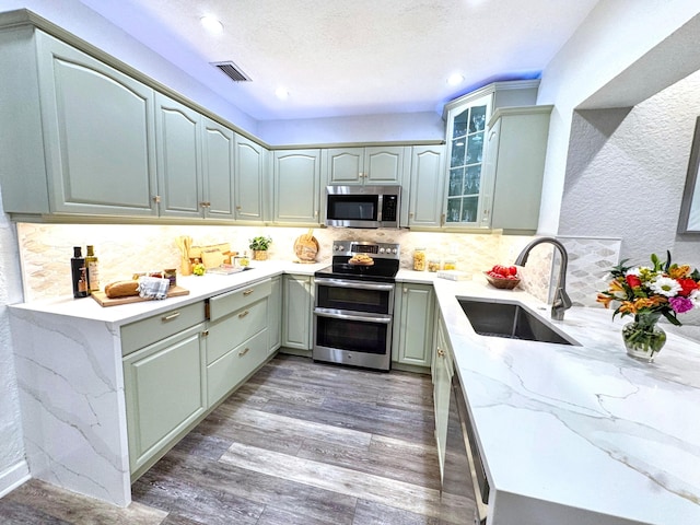 380 Laurie Rd, West Palm Beach, FL 33405 - kitchen featuring stainless steel appliances, a sink, light stone countertops, wood finished floors, and recessed lighting