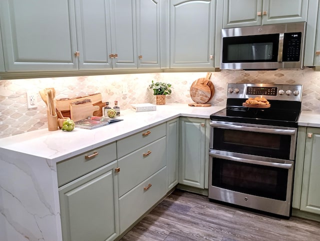 380 Laurie Rd, West Palm Beach, FL 33405 - kitchen featuring stainless steel appliances, decorative backsplash, dark wood-style floors, and light stone counters