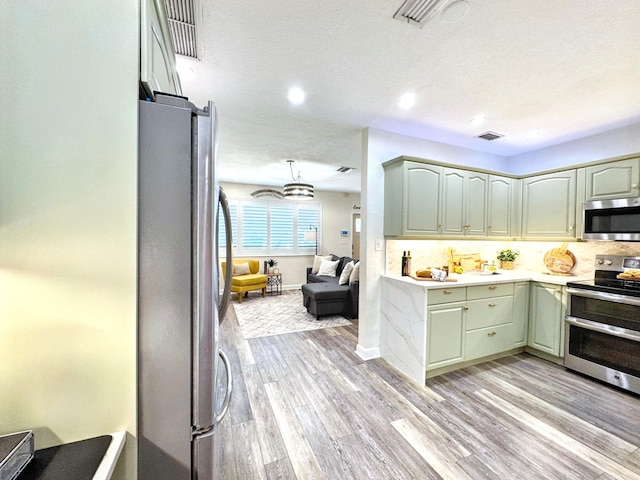 380 Laurie Rd, West Palm Beach, FL 33405 - kitchen with appliances with stainless steel finishes, light wood-style flooring, light countertops, decorative backsplash, and recessed lighting