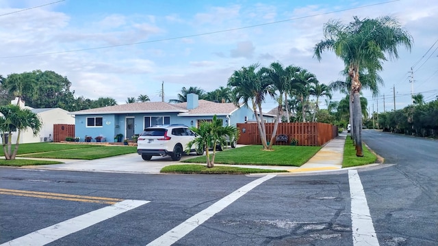 view of front of house with fence, driveway, stucco siding, and a front yard