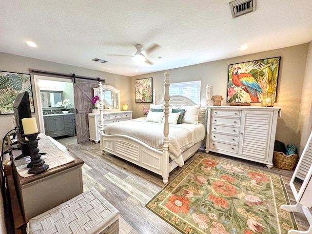 380 Laurie Rd, West Palm Beach, FL 33405 - bedroom featuring a barn door, light wood-style flooring, a textured ceiling, ceiling fan, and recessed lighting