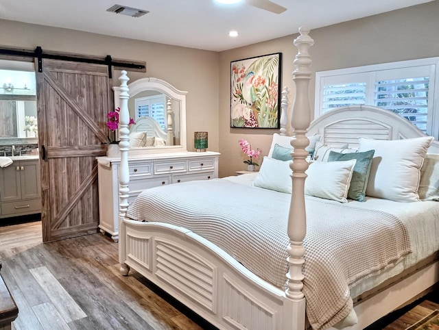 380 Laurie Rd, West Palm Beach, FL 33405 - bedroom with a barn door, wood finished floors, recessed lighting, a sink, and ensuite bathroom
