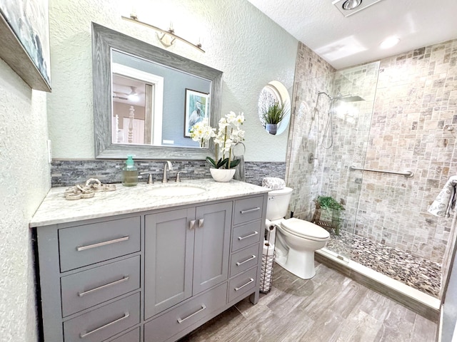 380 Laurie Rd, West Palm Beach, FL 33405 - full bathroom featuring a textured wall, toilet, a tile shower, vanity, and wood finished floors