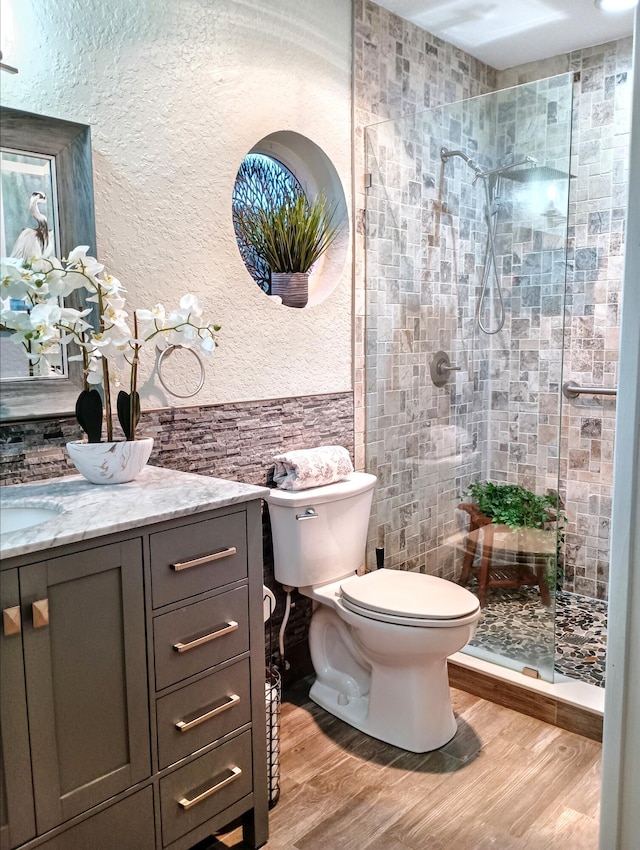 380 Laurie Rd, West Palm Beach, FL 33405 - full bath featuring toilet, vanity, tiled shower, wood finished floors, and a textured wall