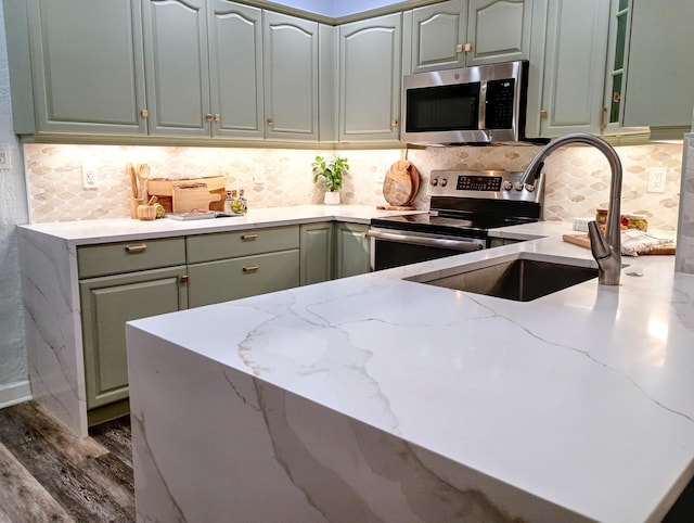 kitchen featuring green cabinetry, dark wood-style flooring, light stone countertops, and appliances with stainless steel finishes