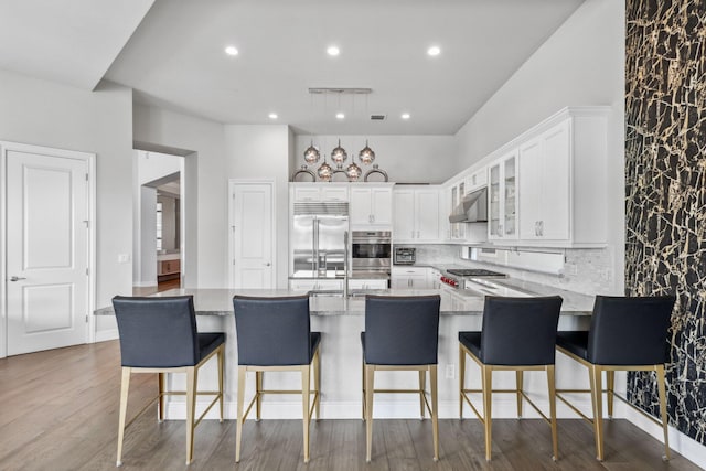 6950 NW 25th Way, Boca Raton, FL 33496 - kitchen featuring stainless steel built in refrigerator, under cabinet range hood, light stone countertops, white cabinets, and a peninsula