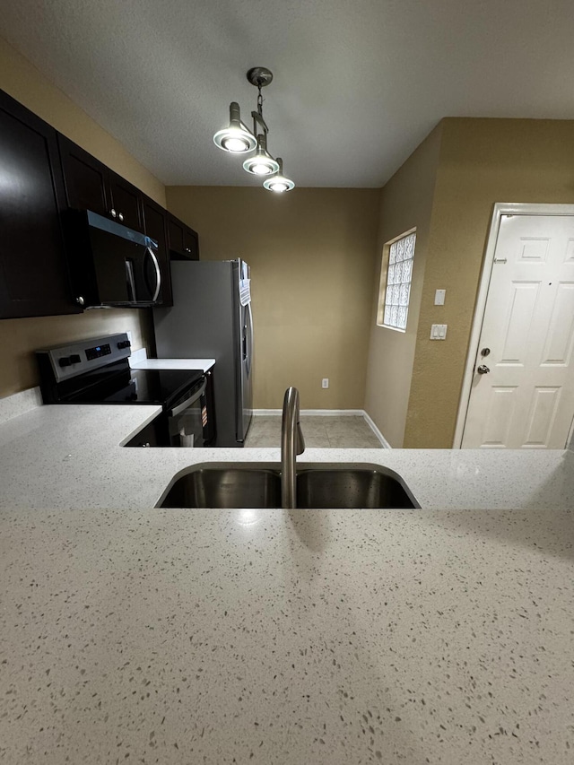 1103 Golden Lakes Blvd Unit 1011, West Palm Beach, FL 33411 - kitchen featuring appliances with stainless steel finishes, a sink, dark cabinetry, baseboards, and pendant lighting