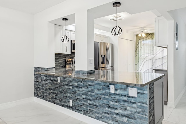 kitchen with ceiling fan, appliances with stainless steel finishes, a peninsula, dark stone counters, and white cabinetry