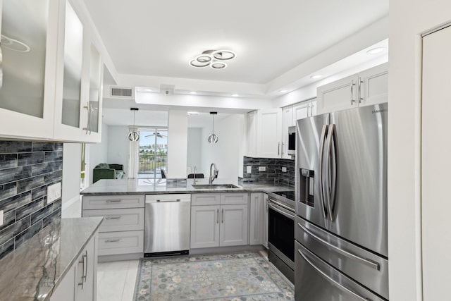 kitchen with a sink, appliances with stainless steel finishes, light stone countertops, and visible vents