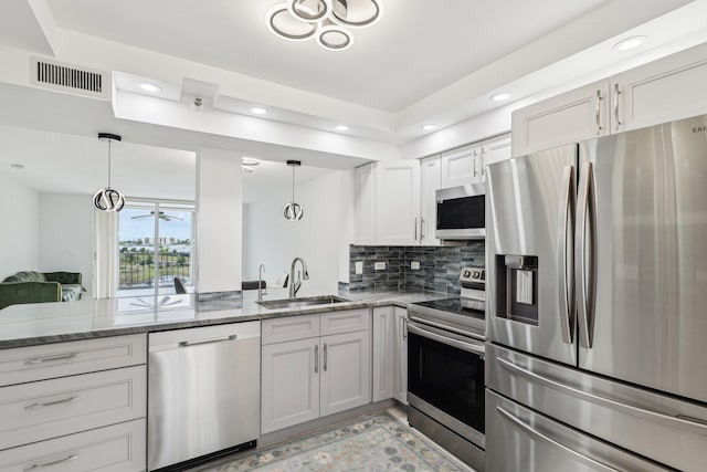 kitchen with visible vents, a peninsula, light stone countertops, a sink, and stainless steel appliances