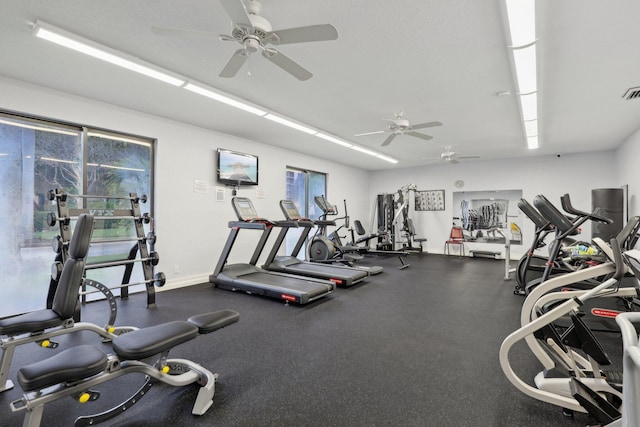 gym with a ceiling fan, baseboards, and a healthy amount of sunlight
