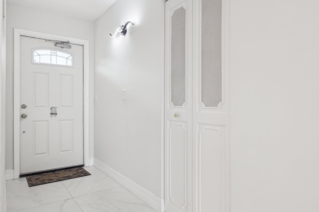 doorway to outside featuring baseboards and marble finish floor