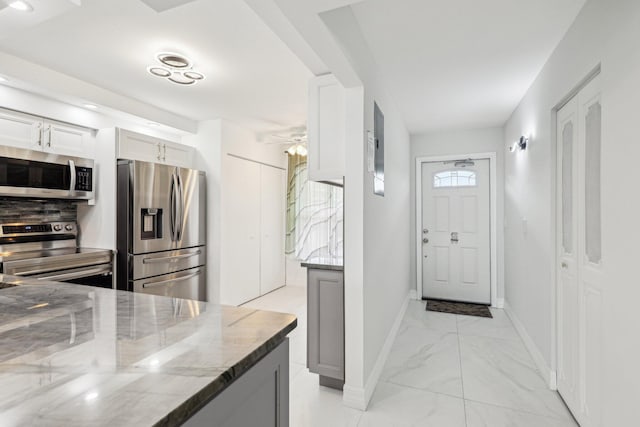 kitchen with a ceiling fan, light stone countertops, appliances with stainless steel finishes, and marble finish floor