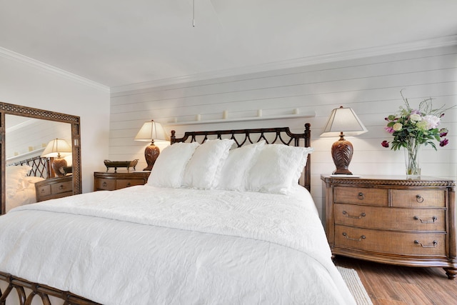 bedroom with wood walls, ornamental molding, and dark wood finished floors