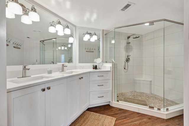 bathroom with a sink, a stall shower, wood finished floors, and visible vents