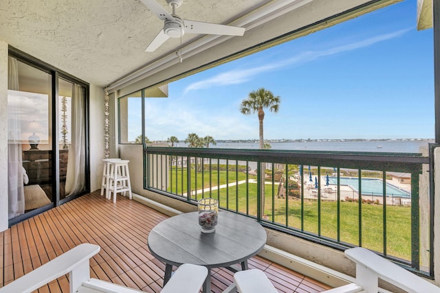 balcony featuring a water view and ceiling fan