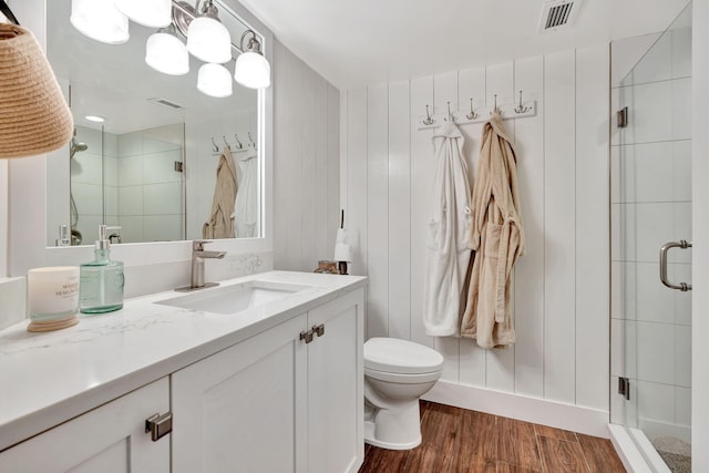 full bathroom featuring vanity, toilet, a shower stall, wood finished floors, and visible vents