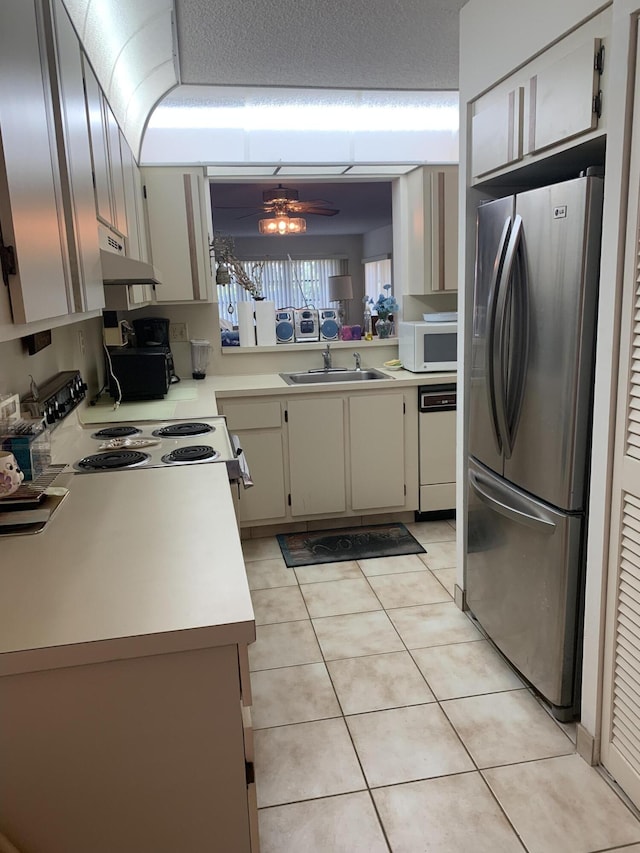 kitchen with under cabinet range hood, white appliances, light countertops, and a sink