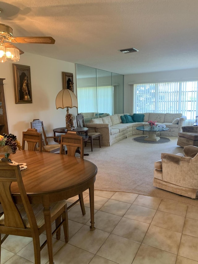 living room featuring a wealth of natural light, visible vents, light tile patterned floors, and light carpet