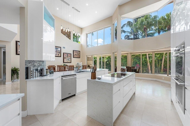 17906 Aberdeen Way, Boca Raton, FL 33496 - kitchen featuring modern cabinets, appliances with stainless steel finishes, a center island, a high ceiling, and light countertops