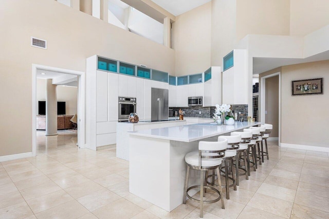 17906 Aberdeen Way, Boca Raton, FL 33496 - kitchen with stainless steel appliances, a towering ceiling, a peninsula, tasteful backsplash, and a kitchen bar