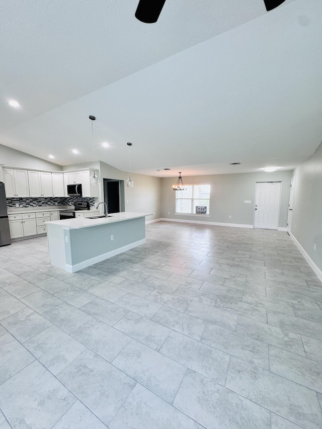kitchen featuring decorative backsplash, a sink, open floor plan, stainless steel appliances, and white cabinetry