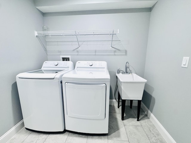 clothes washing area featuring laundry area, baseboards, and washer and dryer