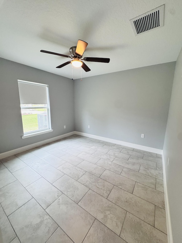 empty room featuring ceiling fan, visible vents, and baseboards