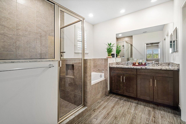 12949 Anthorne Ln, Boynton Beach, FL 33436 - full bathroom featuring double vanity, recessed lighting, wood finished floors, a garden tub, and a stall shower