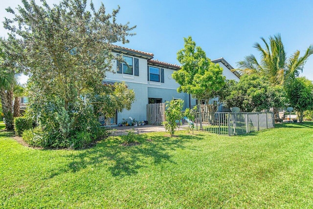 12949 Anthorne Ln, Boynton Beach, FL 33436 - rear view of house with fence, stucco siding, a lawn, and a tiled roof