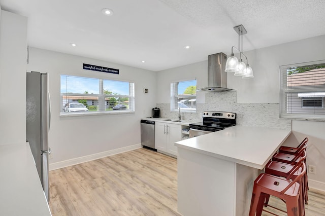124 Mockingbird Ln Unit 124, Delray Beach, FL 33445 - kitchen with island exhaust hood, appliances with stainless steel finishes, light wood-style flooring, a sink, and a kitchen breakfast bar