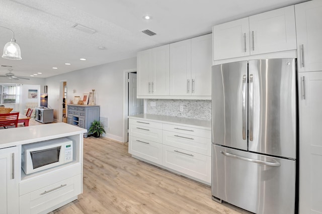 124 Mockingbird Ln Unit 124, Delray Beach, FL 33445 - kitchen with freestanding refrigerator, white microwave, light countertops, white cabinets, and tasteful backsplash