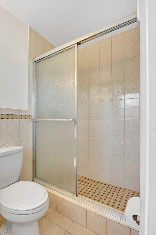124 Mockingbird Ln Unit 124, Delray Beach, FL 33445 - bathroom featuring a stall shower, toilet, tile walls, and tile patterned floors