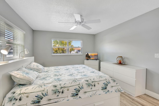 124 Mockingbird Ln Unit 124, Delray Beach, FL 33445 - bedroom with light wood-style flooring, baseboards, a textured ceiling, and a ceiling fan