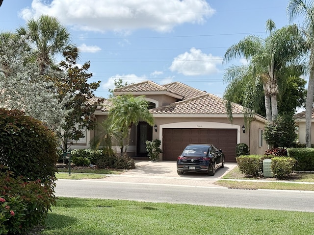 mediterranean / spanish-style home with a tiled roof, an attached garage, driveway, and stucco siding