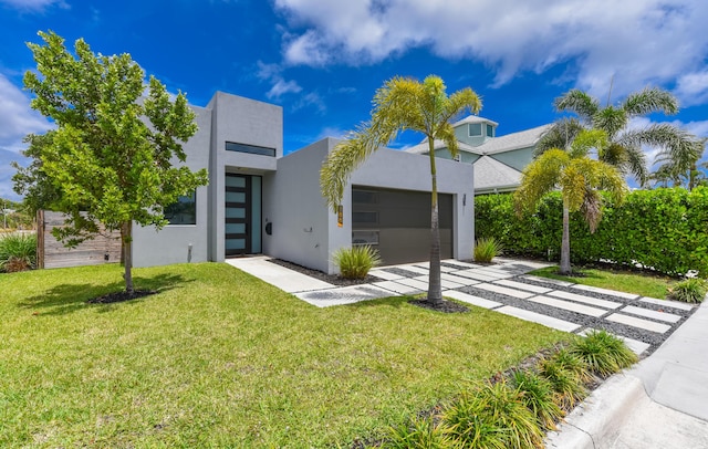 188 Yale Dr, Lake Worth Beach, FL 33460 - modern home featuring a front yard, a garage, stucco siding, and driveway