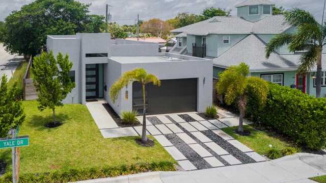 188 Yale Dr, Lake Worth Beach, FL 33460 - contemporary house featuring an attached garage, stucco siding, concrete driveway, a shingled roof, and a front yard