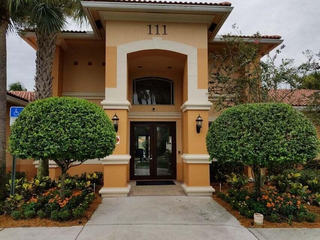 view of exterior entry featuring french doors and stucco siding