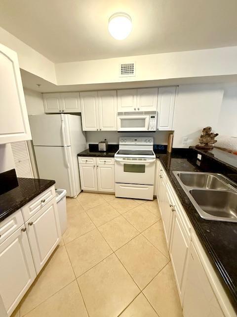 kitchen with white appliances, light tile patterned floors, visible vents, and a sink