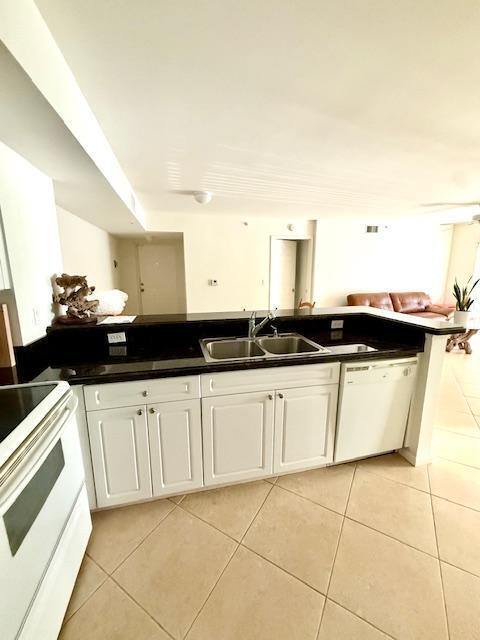242 Village Blvd Unit 2203, Tequesta, FL 33469 - kitchen with white appliances, a sink, light tile patterned flooring, and white cabinets