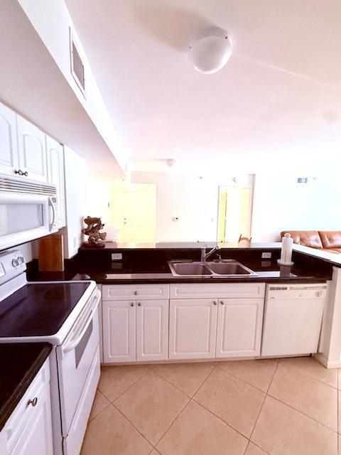 kitchen with light tile patterned floors, visible vents, a sink, and white appliances