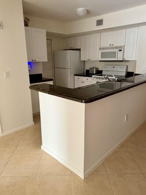 242 Village Blvd Unit 2203, Tequesta, FL 33469 - kitchen featuring white appliances, light tile patterned flooring, and white cabinetry