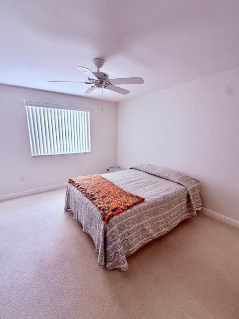bedroom featuring a ceiling fan, light carpet, and baseboards