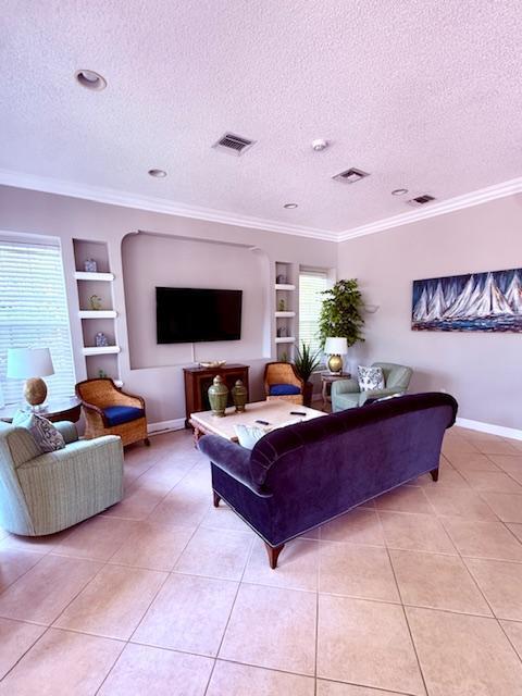 living area featuring a wealth of natural light, a textured ceiling, built in features, and light tile patterned floors