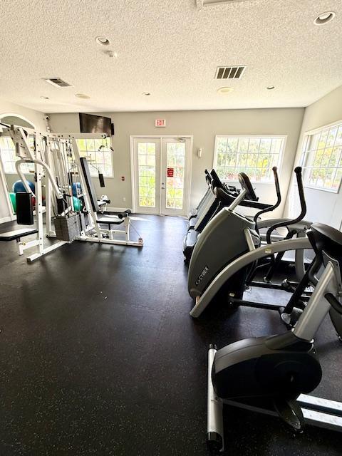 gym with baseboards, visible vents, and a textured ceiling
