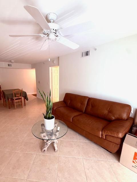 living area with light tile patterned floors, visible vents, and a ceiling fan