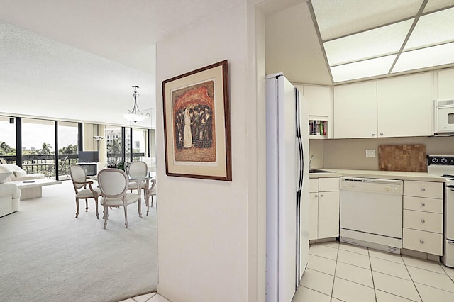 kitchen featuring floor to ceiling windows, light colored carpet, light countertops, white cabinets, and white appliances