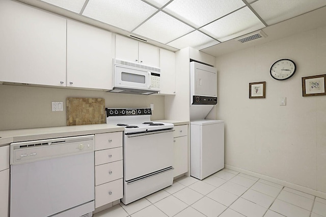 kitchen featuring stacked washer / dryer, visible vents, light countertops, white appliances, and white cabinetry