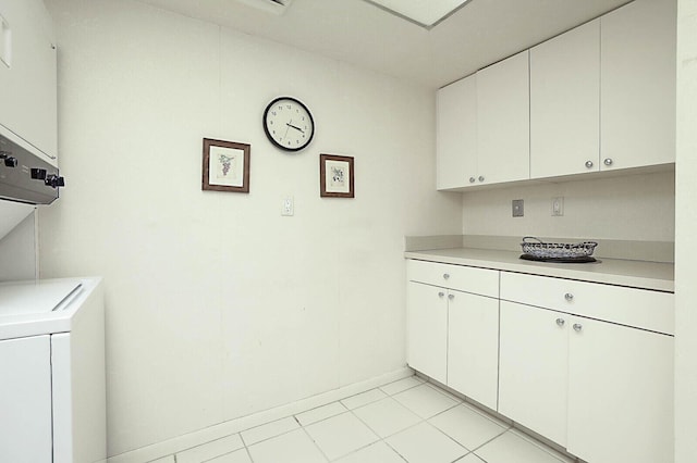 clothes washing area featuring baseboards, stacked washer / drying machine, light tile patterned flooring, and cabinet space