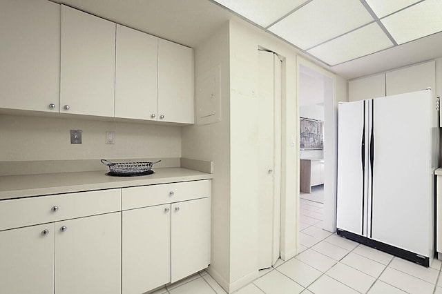 kitchen featuring light countertops, light tile patterned floors, freestanding refrigerator, and white cabinetry